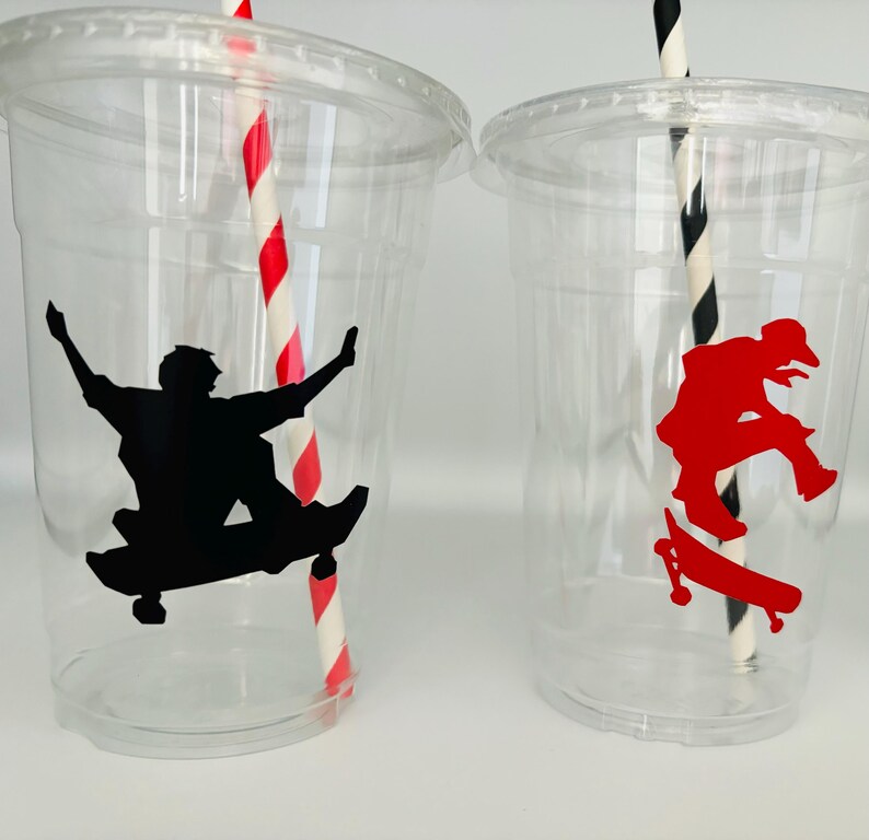 Puede incluir: Dos vasos de pl&aacute;stico transparentes con pajitas rayadas rojas y negras. Un vaso tiene una silueta negra de una persona haciendo skate, el otro tiene una silueta roja de una persona haciendo skate.