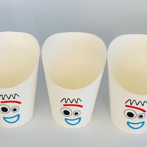 May include: Three white paper food cones with a cartoon face design. Each cone has a black squiggly line for hair, a red line for a mouth, two black oval eyes, and a blue smile. The cones are empty and ready to be filled.
