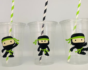 May include: Three clear plastic cups with black and green ninja character designs and green and white striped straws.