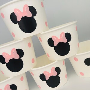 Puede incluir: Conjunto de seis vasos de papel blancos con lunares rosas y un dise&ntilde;o de Minnie Mouse negro y rosa.