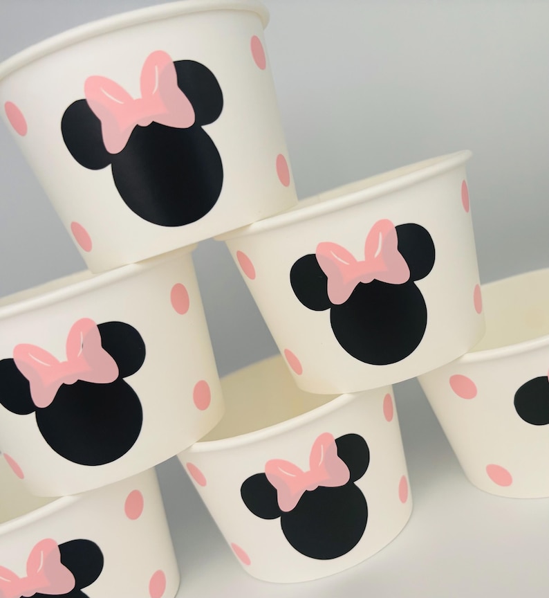 Puede incluir: Conjunto de seis vasos de papel blancos con lunares rosas y un dise&ntilde;o de Minnie Mouse negro y rosa.
