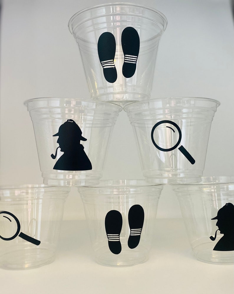 以下が含まれることがあります： 黒いシルエットのデザインが施された透明なプラスチックカップ6個。デザインには、虫眼鏡、足跡、パイプを持った探偵が含まれています。