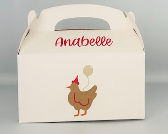 May include: White favor box with a red handle. The box has a brown chicken with a red party hat and a white balloon. The box is personalized with the name "Anabelle".