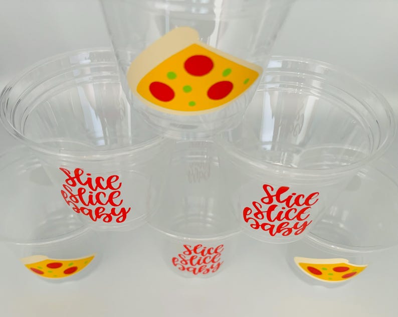 Op de afbeelding: Set van zes doorzichtige plastic bekers met rode en gele pizza-plakjes ontwerpen en de tekst "Slice Slice Baby" op elke beker.