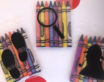 May include: Three clear plastic bags each containing a set of Crayola crayons. The first bag has a magnifying glass, the second bag has two black footprints, and the third bag has a black silhouette of a detective with a pipe.