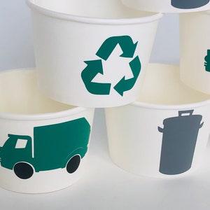 May include: Set of four white paper cups with green and gray recycling themed designs. The designs include a recycling symbol, a garbage truck, and a trash can.