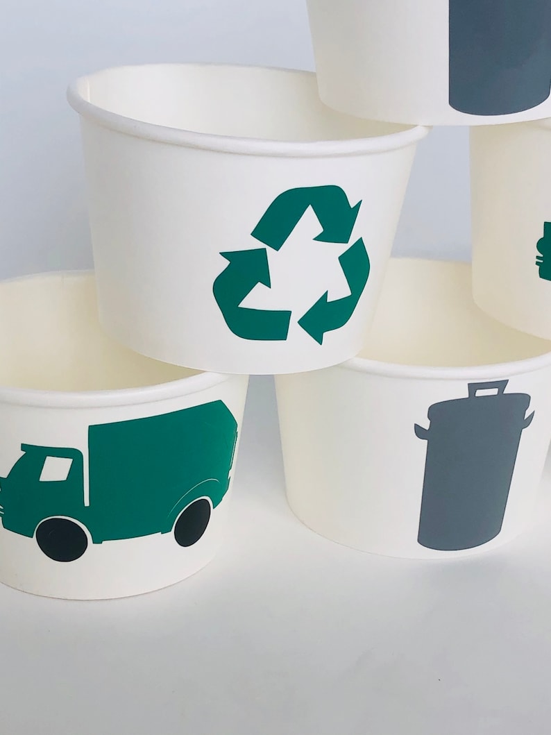 May include: Set of four white paper cups with green and gray recycling themed designs. The designs include a recycling symbol, a garbage truck, and a trash can.