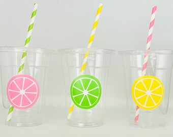 May include: Three clear plastic cups with striped straws and colorful fruit slice stickers. The cups are empty and ready for lemonade or juice.