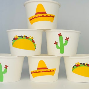May include: Six white paper cups with different Mexican-themed designs. The designs include a yellow sombrero, a green cactus with red flowers, and a yellow taco with green lettuce and red tomatoes.