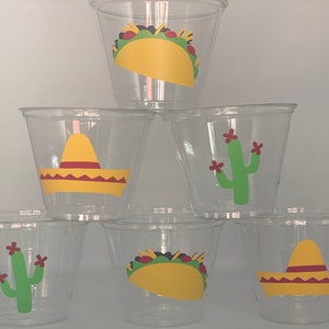 May include: Six clear plastic cups with colorful designs. The designs include a yellow sombrero, a green cactus with red flowers, and a yellow taco.
