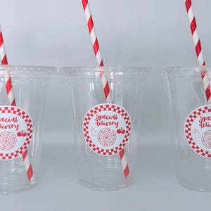 May include: Three clear plastic cups with red and white striped straws. Each cup has a round sticker with a red and white checkered border, the words "Special Delivery", and pizza and tomato illustrations.