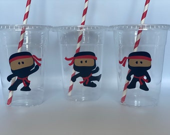 May include: Three clear plastic cups with red and white striped straws. Each cup has a black and red ninja character sticker with a red headband.