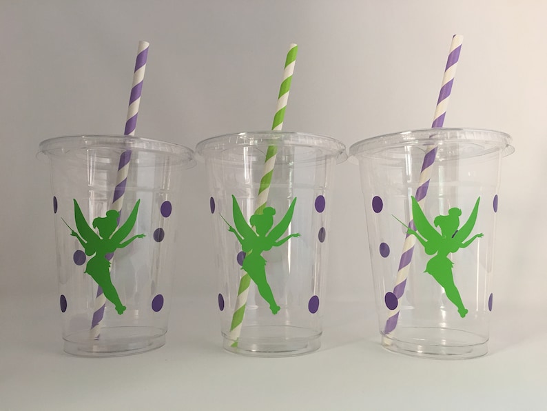 May include: Three clear plastic cups with green fairy silhouettes and purple polka dots. Each cup has a striped straw.
