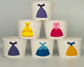 May include: Six white paper cups with princess-themed designs. Each cup features a different princess in a colorful dress. The princesses are Cinderella, Belle, Ariel, Snow White, Rapunzel, and Aurora.