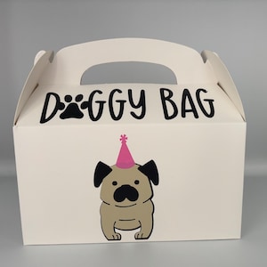 May include: White cardboard gift bag with a handle. The bag has a black paw print and the text "Doggy Bag" printed on the front. A cartoon pug wearing a pink party hat is printed on the front of the bag.