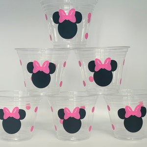 Puede incluir: Seis vasos de pl&aacute;stico transparentes con lunares rosas y un dise&ntilde;o de Minnie Mouse negro y rosa.