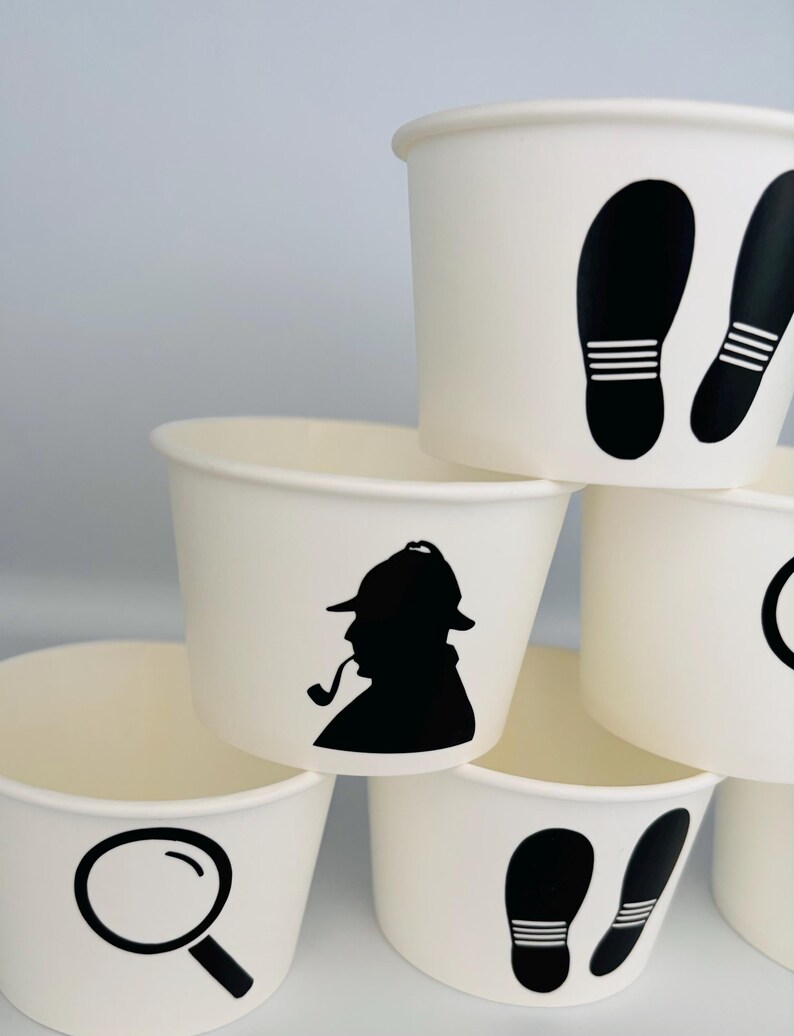 Puede incluir: Conjunto de seis vasos de papel blanco con dise&ntilde;os de silueta negra. Los dise&ntilde;os incluyen una lupa, un detective con una pipa y huellas.