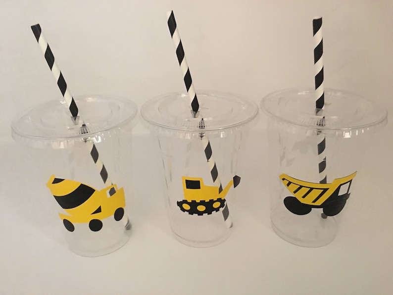 May include: Three clear plastic cups with black and white striped straws. Each cup has a yellow and black construction vehicle sticker on the front. The vehicles are a cement mixer, a backhoe, and a dump truck.