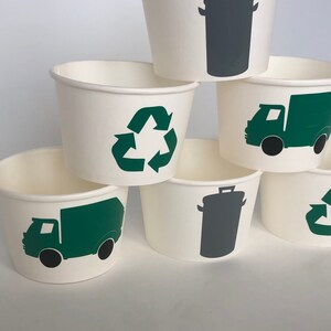 May include: Six white paper cups with green and gray recycling symbols. The symbols include a recycling arrow, a garbage truck, and a trash can.