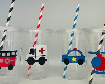 May include: Four clear plastic cups with colourful straws and vehicle themed stickers. The stickers feature a red fire engine, a white ambulance, a blue police car, and a blue helicopter.