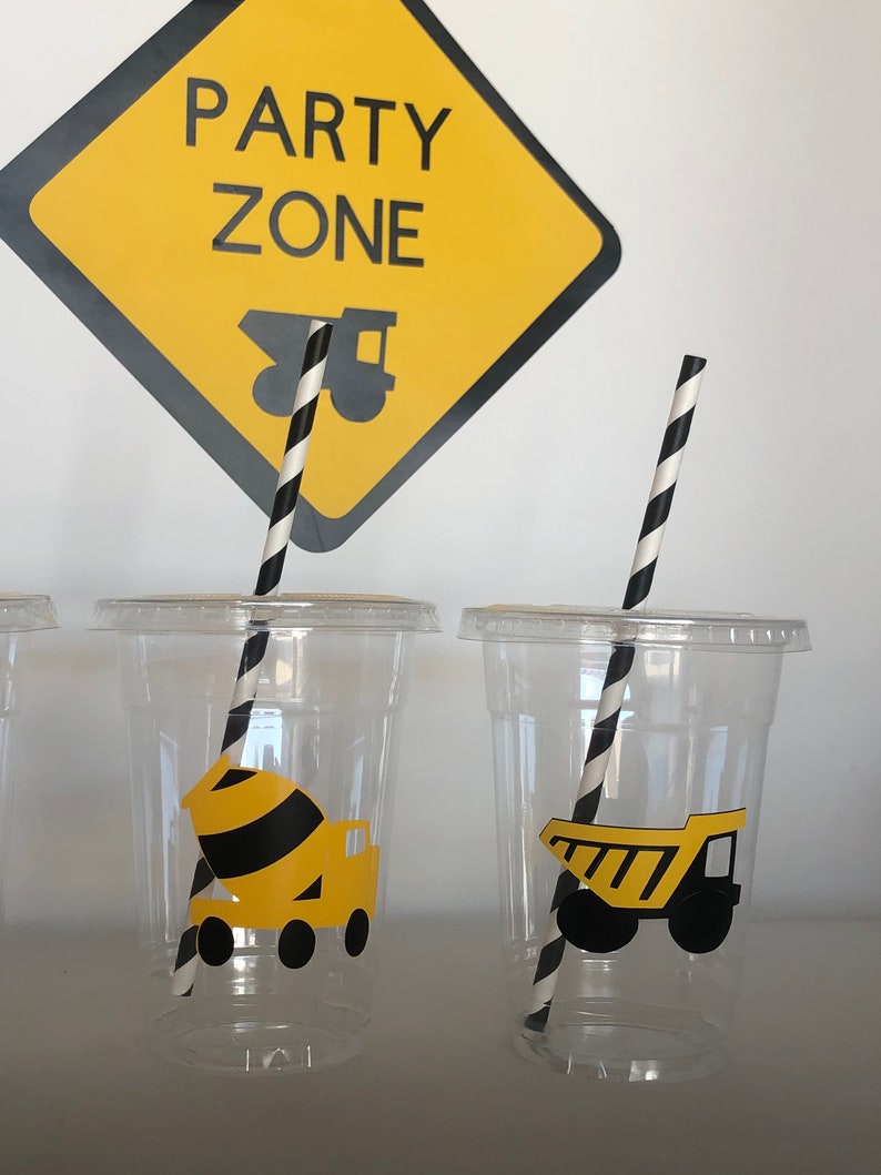 May include: Clear plastic cups with black and white striped straws. Each cup has a yellow construction vehicle sticker. The sign above reads "Party Zone" with a yellow construction truck graphic.