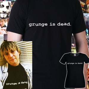 Könnte beinhalten: Schwarzes T-Shirt mit dem Aufdruck "grunge is dead." in weiß auf der Vorderseite. Das Shirt wird von einer Person getragen.