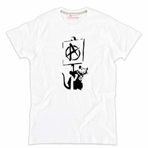 Peut inclure: T-shirt blanc avec un dessin noir d'un rat tenant une pancarte avec un symbole anarchiste. Le rat porte un collier avec un symbole de paix. Le t-shirt a un col rond et des manches courtes.