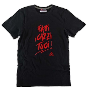 Può includere: T-shirt nero con testo rosso "Fatti i cazzi tuoi!" in un carattere audace e stilizzato. La maglietta ha un girocollo e maniche corte. Un piccolo logo è in basso.
