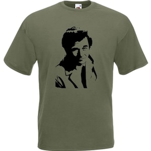 Könnte beinhalten: Ein grünes T-Shirt mit einer schwarzen Silhouette eines Männergesichts.