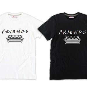 Può includere: Due t-shirt, una bianca e una nera, con la parola "FRIENDS" e un'immagine stilizzata di un divano stampata sul davanti.