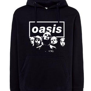 Peut inclure: Sweat à capuche noir avec le nom du groupe "oasis" dans un encadré blanc et un graphisme blanc des membres du groupe. Le sweat-shirt a une poche avant et une capuche à cordon.