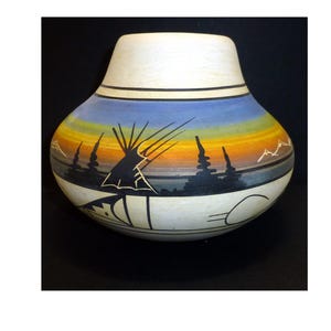 May include: A rounded ceramic vase featuring a painted landscape scene with a sunset gradient of blue, orange, and yellow. The design includes black silhouettes of a teepee, pine trees, and mountain peaks, with a cream-colored neck and base.