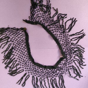 Puede incluir: Borde de flecos negros con cuentas con un diseño de red. El fleco está hecho de pequeñas cuentas negras que se ensartan para crear un efecto delicado y fluido.