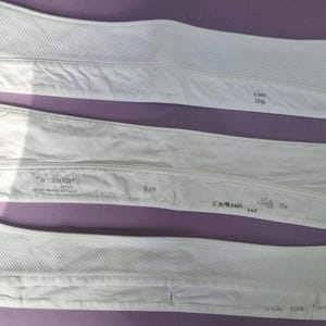 May include: Three detachable white shirt collars. The top collar has a textured weave and the text 15 1/2. The middle collar features the text Wyanar Irish Manufacture, 9/8, and T.A. Ridel 265. The bottom collar has a textured weave.