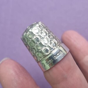 May include: Silver thimble with a floral design and the inscription "925" on the side.