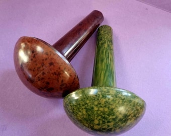 May include: Three decorative pestle and mortar sets. One is a speckled brown, another is a speckled green, and the third is a solid dark brown. The pestles are cylindrical, and the mortars are bowl-shaped. The sets are on a purple background.