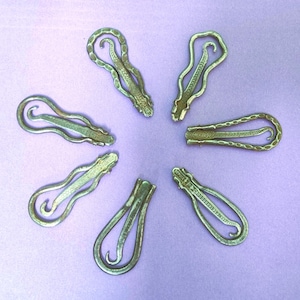 May include: Seven antique silver-toned metal thimbles with intricate designs. The thimbles are arranged in a starburst pattern on a light purple background.