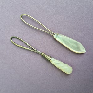 May include: Two vintage silver and mother-of-pearl threaders. One has a simple loop and the other has a twisted handle.