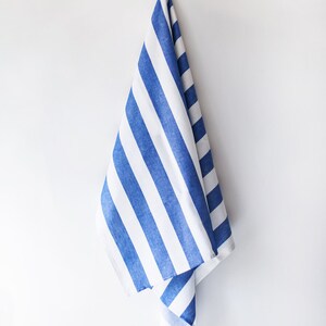 May include: A blue and white striped kitchen towel hanging on a white wall.