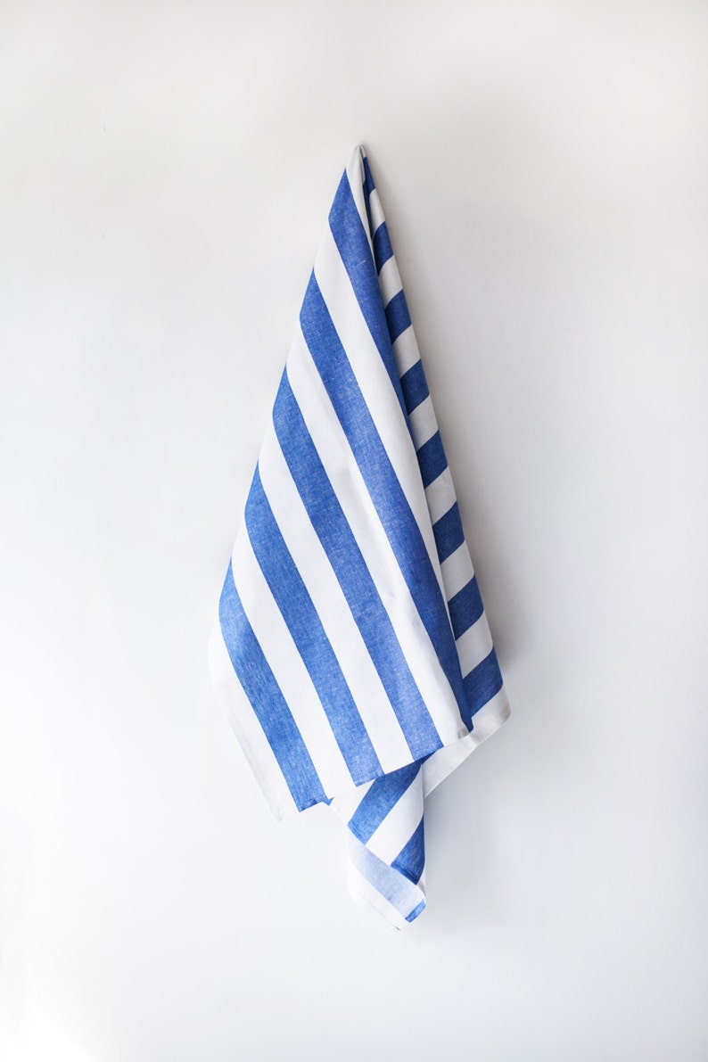 May include: A blue and white striped kitchen towel hanging on a white wall.