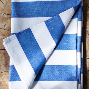 May include: A white and blue striped cotton tablecloth folded on a wooden surface.