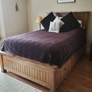 May include: A wooden bed frame with a brown duvet and pillows. The bed has storage drawers underneath.