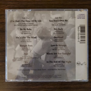 May include: The back of a compact disc case for the soundtrack to the movie "Dirty Dancing". The case is white with black text and features a photo of a couple dancing. The text includes the song titles and artists, as well as the album's executive producer and A&R director.