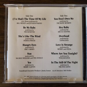 May include: A CD case with a white background and black text listing the songs and artists on the CD. The songs include "(I've Had) The Time Of My Life", "Be My Baby", "She's Like The Wind", "Hungry Eyes", "Stay", "Yes", "You Don't Own Me", "Hey Baby", "Overload", "Love Is Strange", "Where Are You Tonight?", and "In The Still Of The Night".