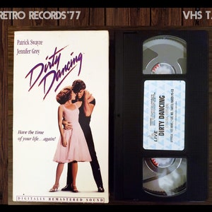May include: VHS tape case for the movie Dirty Dancing, featuring Patrick Swayze and Jennifer Grey on the cover. The text on the case reads "Dirty Dancing", "Have the time of your life...again!" and "Digitally Remastered Sound".