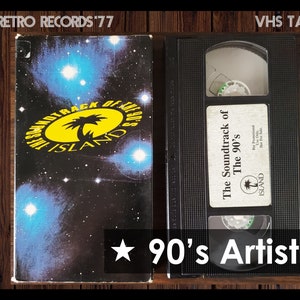 May include: VHS tape titled "The Soundtrack of the 90's" with a black and white image of a palm tree on a yellow circle with the word "ISLAND" in white text. The tape is labeled "Retro Records '77" and "VHS Tape".