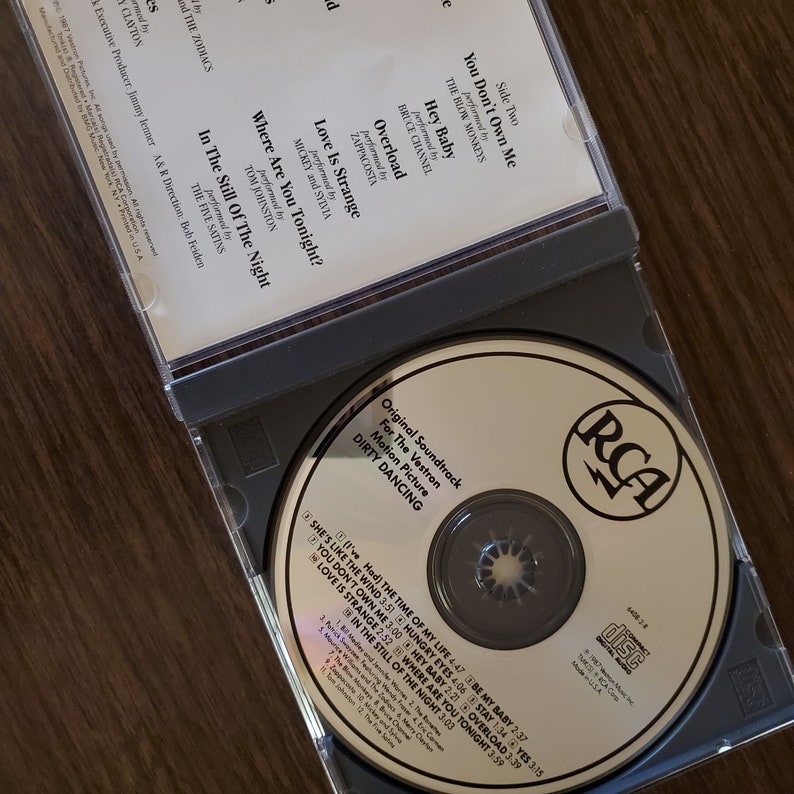 May include: A silver compact disc with a gold RCA logo and the text "Original Soundtrack for the Vestron Motion Picture Dirty Dancing" printed on the front. The disc includes a list of songs from the movie, including "(I've Had) The Time of My Life", "She's Like the Wind", "Hungry Eyes", and "Love Is Strange".