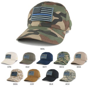 May include: A collection of baseball caps in various colors, each featuring a patch of the American flag with a blue line. The caps are in shades of tan, olive, navy, and camouflage. The main cap is camouflage.