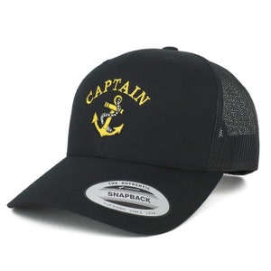 May include: Black and yellow embroidered trucker cap with the word "CAPTAIN" and an anchor. The cap has a black mesh back and a black snap closure. The label on the cap reads "THE AUTHENTIC SNAPBACK YUPOONG SINCE 1974."