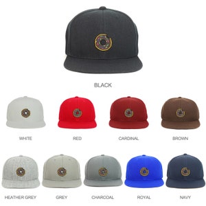 May include: A selection of ten baseball caps in various colors, each featuring an embroidered donut with sprinkles. The colors include black, white, red, cardinal, brown, heather grey, grey, charcoal, royal blue, and navy.